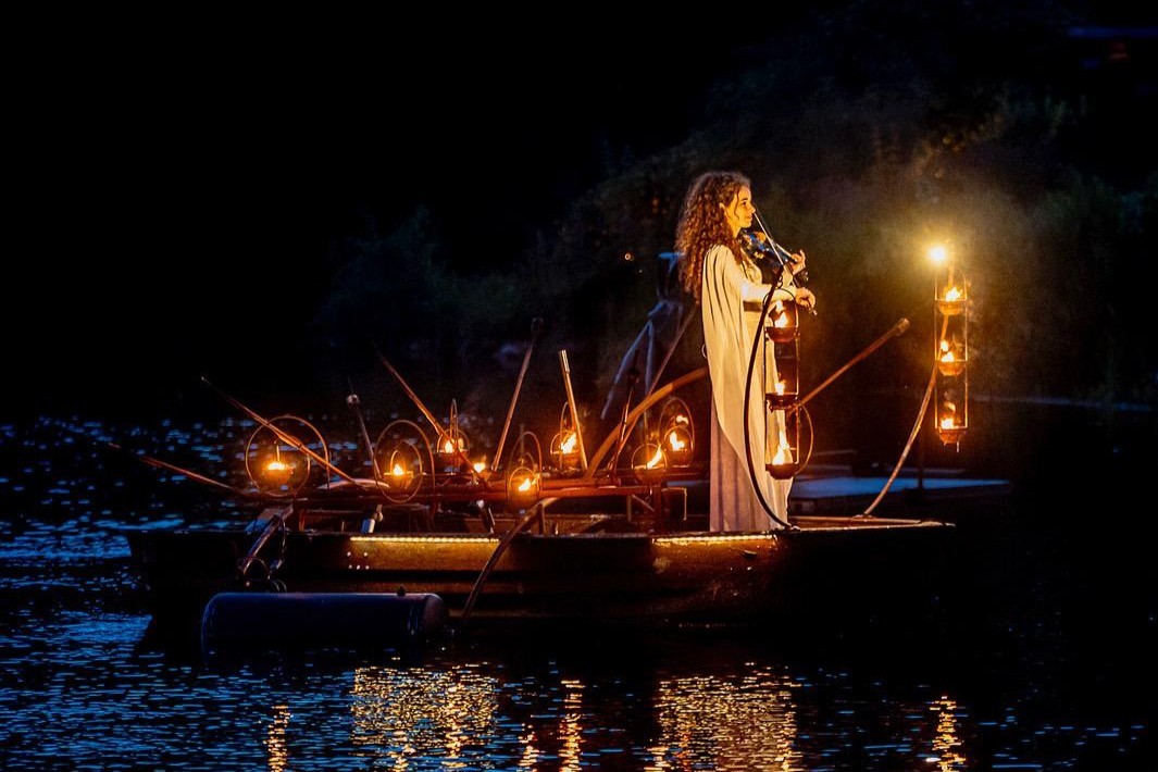 Muzikant speelt 's nachts op een sfeervol verlicht bootje in het water.